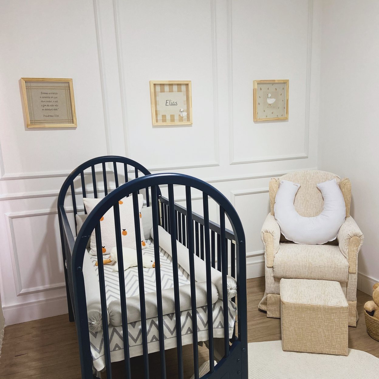 Quarto claro com berço preto e três bastidores bordados na parede