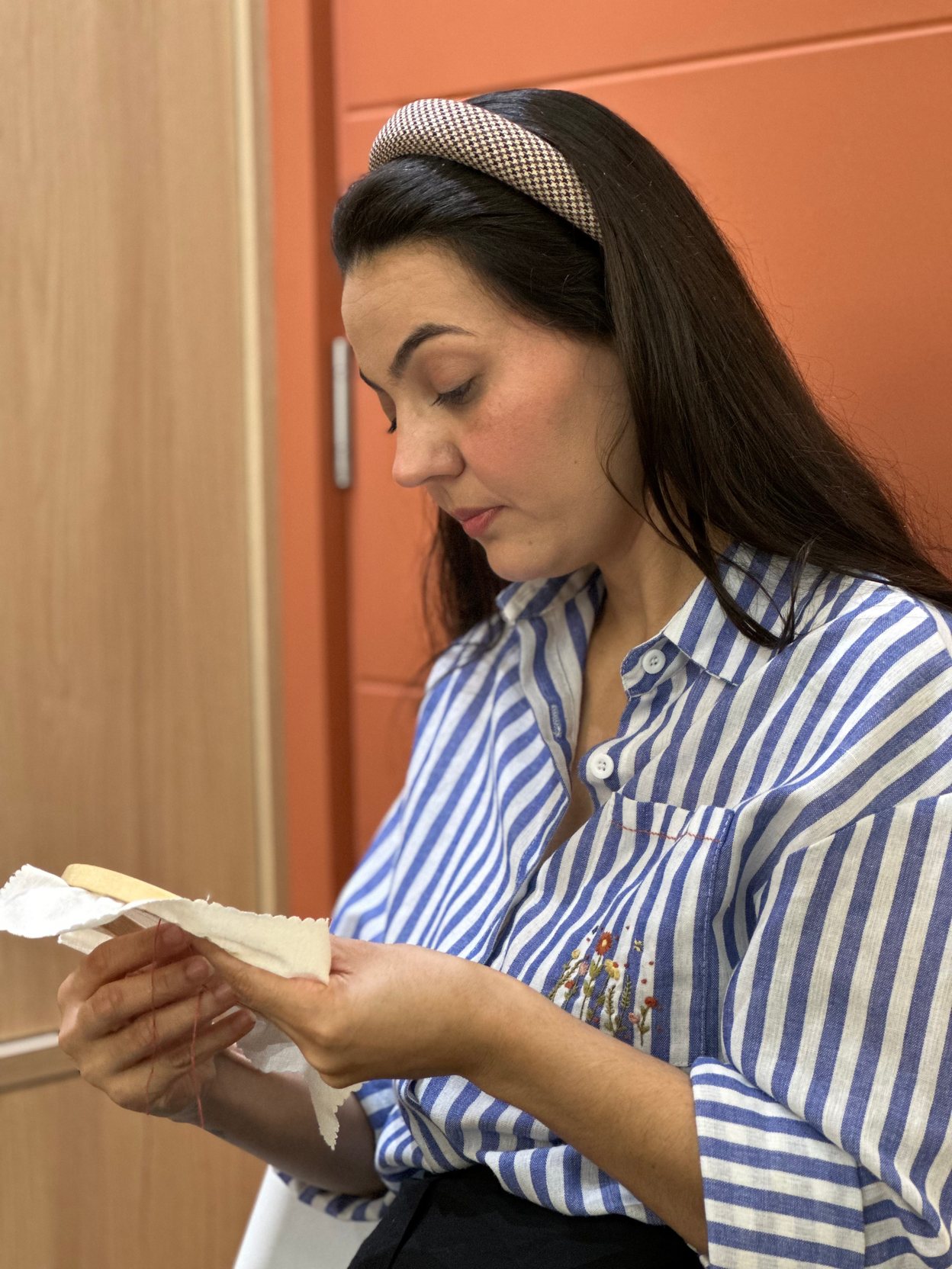 Pamela Berger no ateliê, examinando um bordado