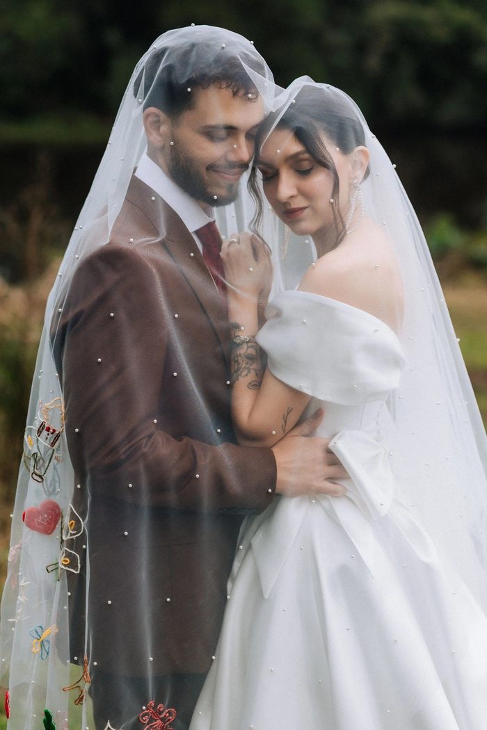 Casal abraçado sob o véu bordado